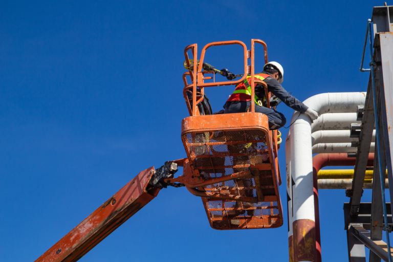 Male industry working at high in a boom lift inspection thickness of pipeline oil